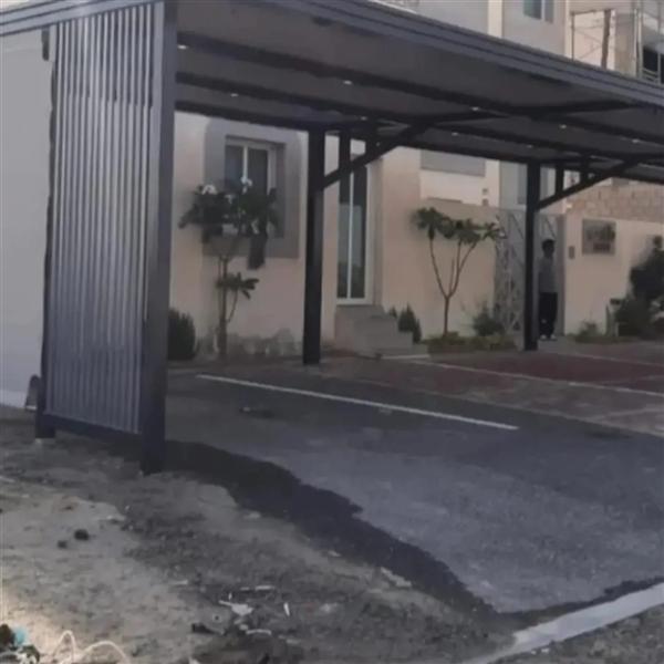 مظلة سيارات داكنة مع جدار جانبي من الشرائح الحديد